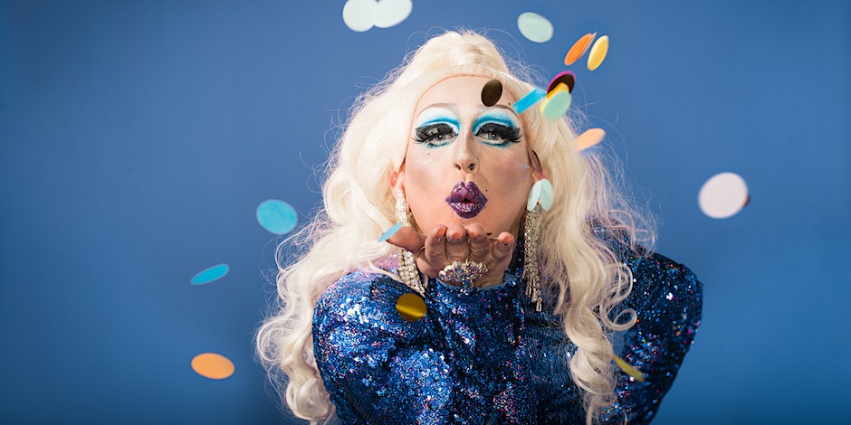 A drag artist blowing glitter towards the camera